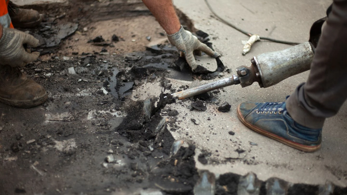 Breaking up the old driveway and preparing the base for a new asphalt driveway.